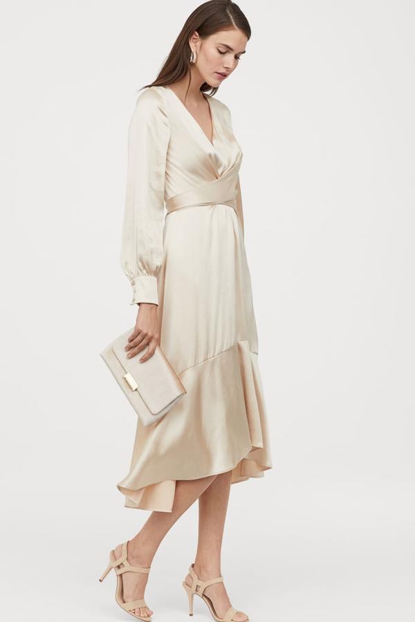 Vestido midi en satén fluido con brillo, escote de pico y tiras anchas cruzadas delante que se anudan en la espalda (59,99 euros). Lleva mangas fruncidas, puños anchos con botones revestidos y cremallera oculta detrás. La falda de vuelo lleva un volante amplio en el bajo. Va sin forrar.