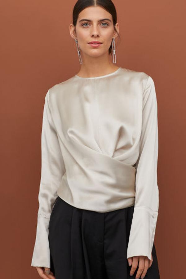 Top ancho en seda fluida suave (99 euros). Lleva cuello redondo, botón revestido en la nuca y mangas largas con puños anchos con botón revestido.