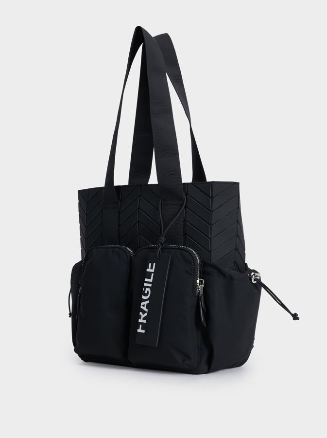 Con cuatro bolsillos negros rodeando tres de las caras del bolso, con aplicaciones que imitan el dibujo de una llanta. Cuesta 29,99 euros, es de Parfois y se quedaría en 24.