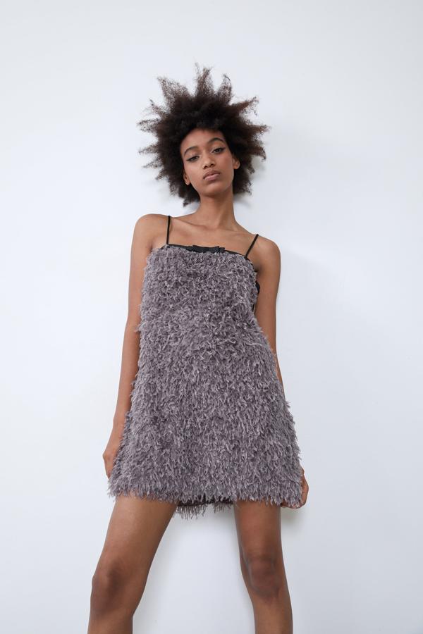 El efecto pluma también llega a los vestidos cortos, y Zara tiene esta versión en gris con tirantes finos. El escote comienza en tejido satinado negro con lazo. Está disponible en seis tallas, de la XS a la XXL, y cuesta 25,95 euros.
