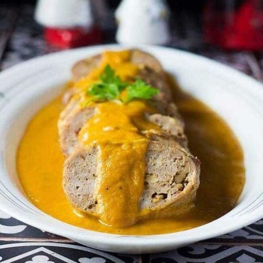 Ingredientes para el fiambre de pollo:-500 gr de carne de pollo picada-75 gr de queso curado rallado75 gr de nueces-50 gr de dátiles-1 huevoPreparación:Picamos los dátiles y las nueces. A continuación picamos el pollo, y mezclamos todos los ingredientes.Extendemos un trozo de film, colocamos la mitad de la mezcla en el centro, damos forma de salchicha, cerramos y atamos las puntas. Hacemos lo mismo con la otra mitad de la carne picada.Cocinamos cada fiambre por separado en el microondas, a máxima potencia 3’, damos la vuelta y 3’ más.Ingredientes para los rollitos en salsa:-2 rollitos de fiambre de pollo casero-1 puerro-1/2 cebolla-3 zanahorias-1 hoja de laurel-2 vasos de caldo de pollo-1 cda harina espelta-AOVE-Pimienta y salPreparación:Sofreímos la cebolla, el puerro y la zanahoria con un sal y pimienta. Añadimos el caldo con el laurel, esperamos a que hierva y dejamos a fuego medio 30’.Introducimos los rollitos de pollo. Les damos la vuelta y enseguida los sacamos, sólo queremos que se calienten.Trituramos la salsa y cubrimos con ella el fondo de la fuente de servir. Encima los rollitos cortados en rodajas de un par de centímetros y, por encima, un poco más de salsa.