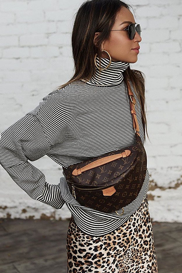 El look de Sincerely Jules con jersey de rayas, falda midi estampada de leopardo y riñonera de Louis Vuitton: un diez.