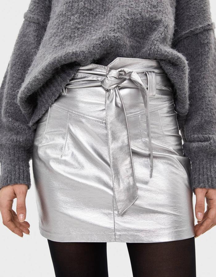 Falda mini con cinturón metalizada de Bersdhka (25,99 euros).