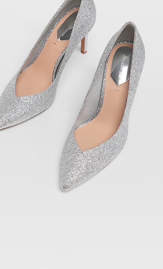 Con acabado glitter plateado y tacón de 8 centímetros, en Stradivarius puedes encontrar este par de zapatos acabados en punta por 22,99 euros. Está disponible entre los números 36 y 41.