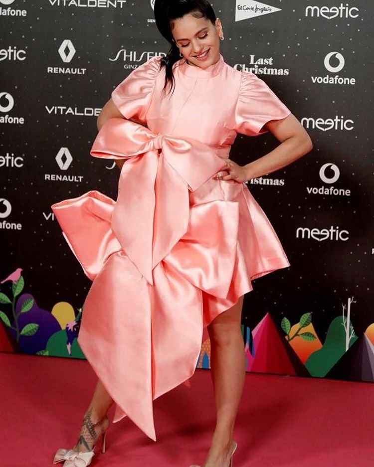 volvemos a nuestro país, para descubrir el estilismo más imposible de  Rosalía. Aunque 2019 ha sido su año , profesionalmente hablando, y se ha convertido en uno de los famosos más admirados y demandados del momento… lo de sus looks no ha acabado de cuajar. Aunque cuesta elegir solo uno de sus estilismos, nos vamos a quedar con  este vestido lleno de lazos XXL que lució para una entrega de premios  y que combinó con unos stilettos también con lazos a juego.