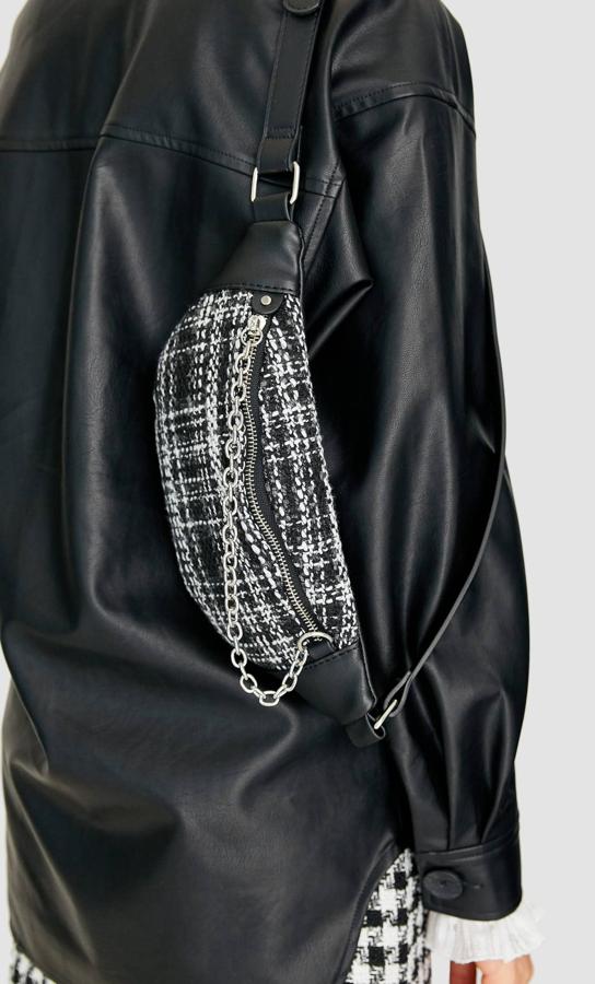 Para las que salen con lo justo de casa y no se pierden una tendencia esta riñonera tweed de Stradivarius en tonos negros y grises es perfecta. El cierre viene acompañado de una cadena que cruza la bolsa. Tiene un precio de 12,99 euros.