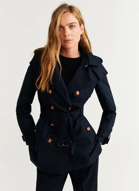 Trench corto doble botonadura en tono azul marino oscuro. ¿Su precio? 39,99 euros. (Antes: 59,99 euros). Fíchalo en Mango.