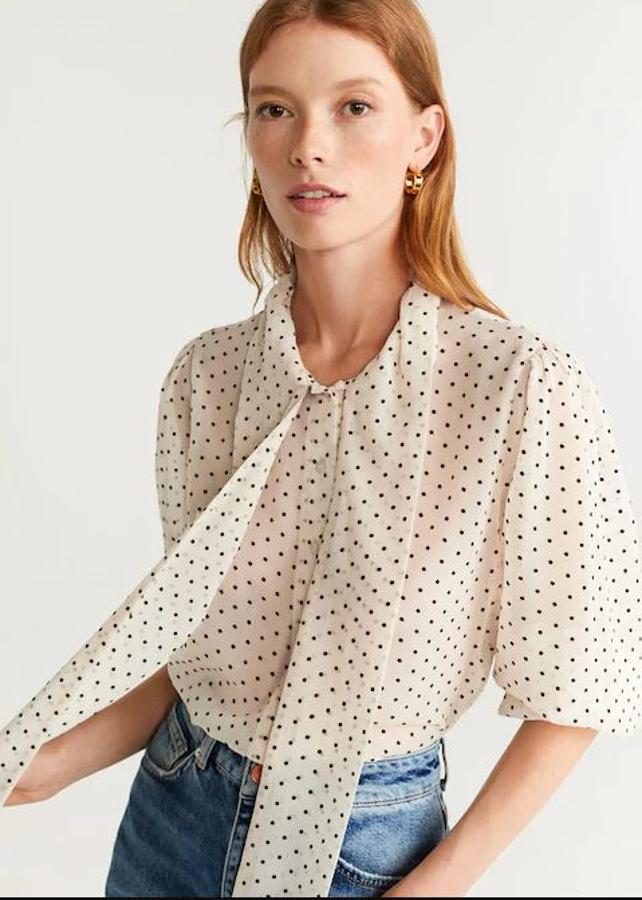 Las más clásicas encuentran en esta blusa de Mango su emjor alida. Blanca, con pequeños puntitos en negro y una lazada para hacer en el cuello. Está a 19,99 euros pero costaba 29,99 en temporada.