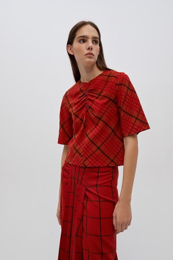 Para aquellas que busquen una prenda con la que completar su look en rojo, Sfera tiene este cuerpo con frunces en el frontal y manga corta. Cuesta 29,99 euros y está disponible entre las tallas S y L.