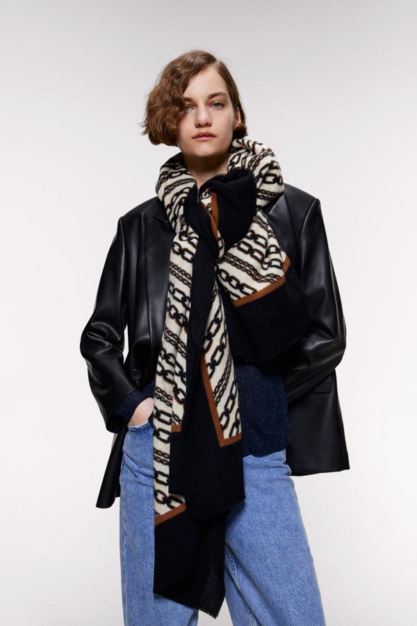 Para las que más que un pañuelo, buscan un fular, uno de los más bonitos de Zara es este de cadenas sobre beige encuadradas en negro y marrón. Con acabado deshilachado, cuesta 19,95 euros.