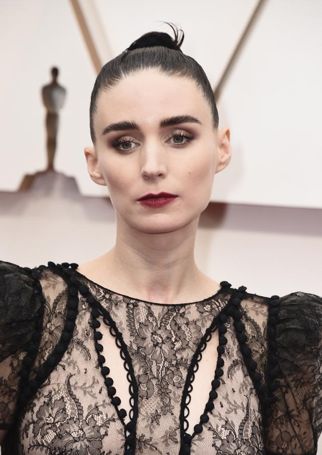 La actriz acompañaba a su pareja, el recién oscarizado Joaquin Phoenix, y optó por un look beauty que refuerza la languidez romántica de su rostro: moño alto estilo top knot, piel pálida e impecable, smoky eye con sfumatto en las cuencas, pestañas elongadas, cejas definidas y labios granates de efecto mordido.