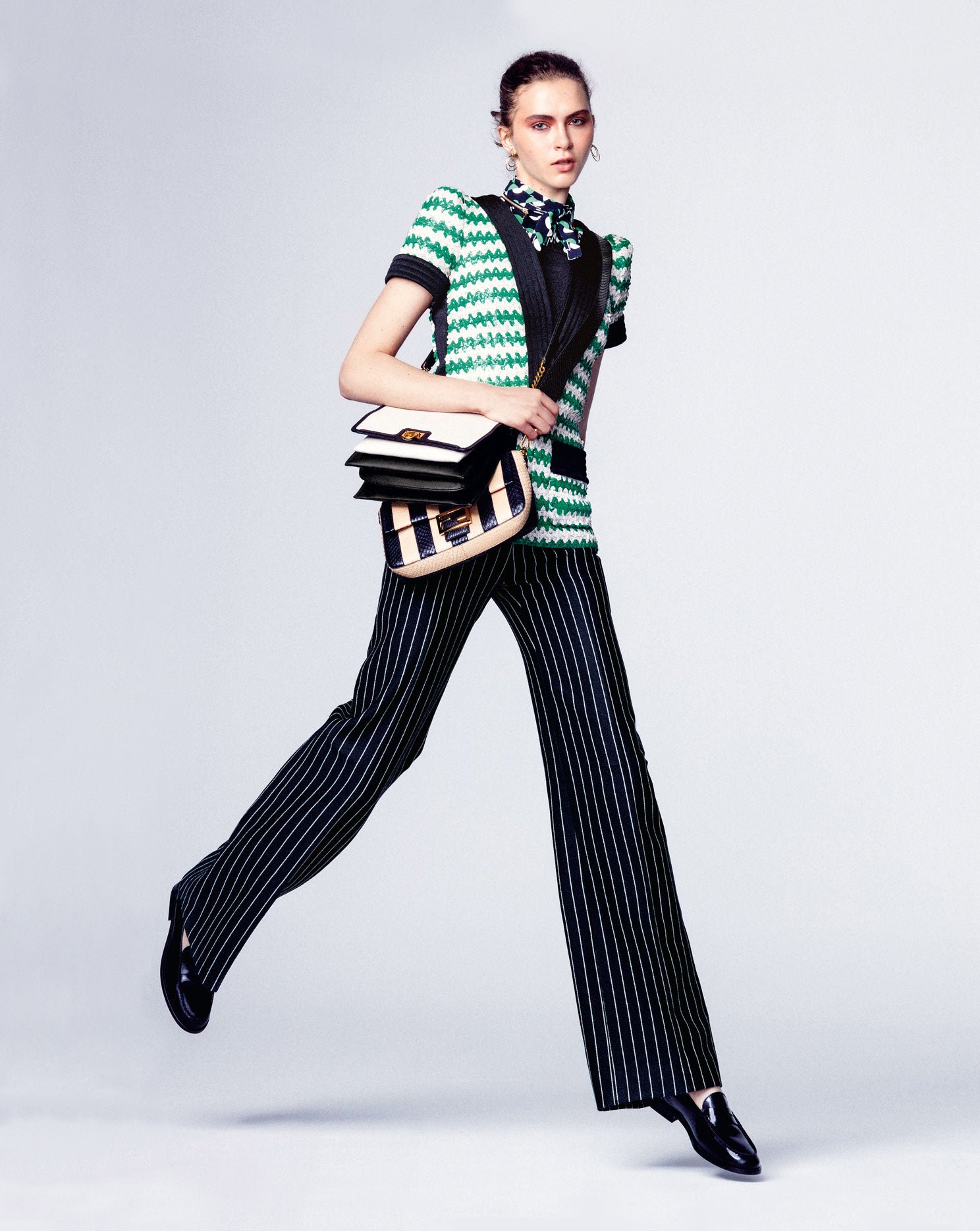 Blusa de seda con lazada, jersey de manga corta y pantalón, todo de Louis Vuitton. Los mocasines son de Tod’s; el bolso bandolera de cuero blanco y negro, de Salvatore Ferragamo; y el baguette de rayas negras y beige, de Fendi. Pendientes de Aristocrazy.