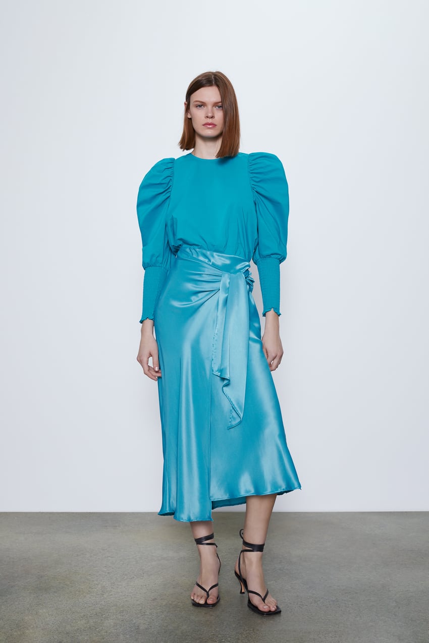 Una de nuestras favoritas para looks de invitada: falda asimétrica en tono azul bebé con lazo en la cintura, ideal para disimular cadera y reducir tripa. (29,95 euros).