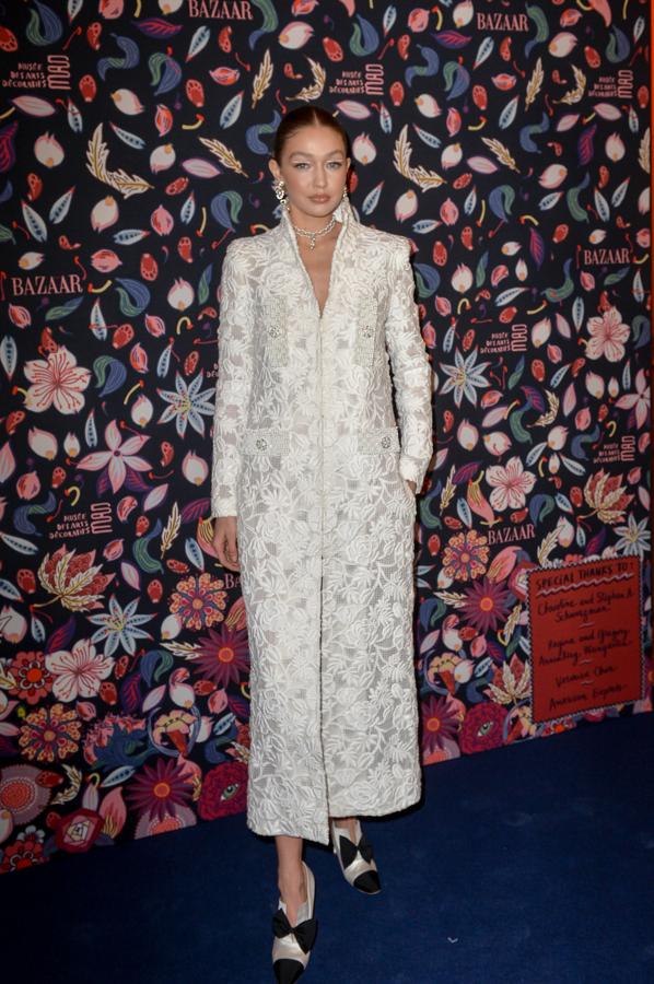 Gigi Hadid con un vestido blanco tipo abrigo de tejido brocado.