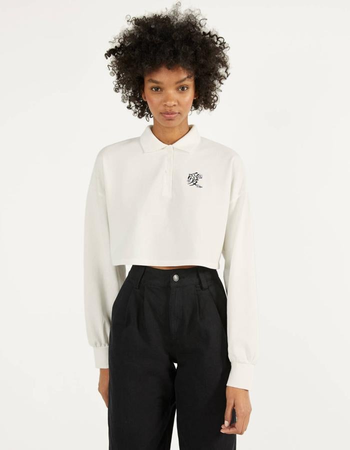 Polo cropped blanco de Bershka con bordado en el pecho (9,99 euros).