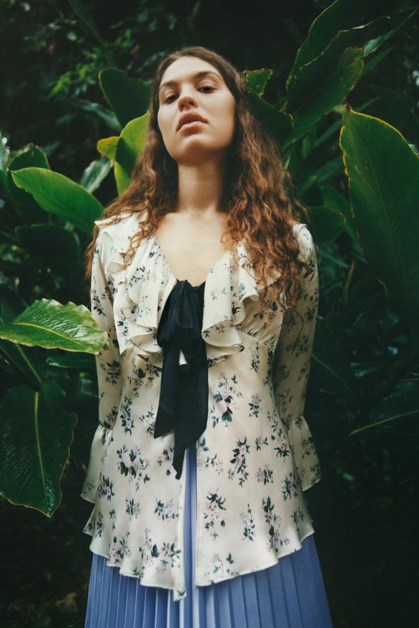 Blusa romántica, en tejido de raso con volante y lazada negra en el escote, 29,95 euros. De la nueva colección de primavera de Zara, Lost garden.