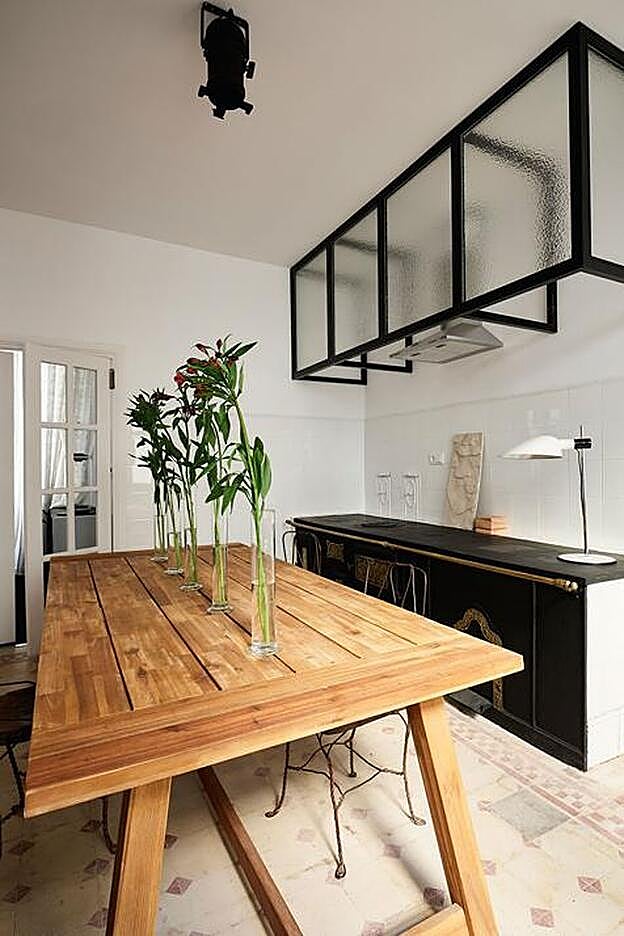 La cocina, corazón del estudio, conserva las baldosas hidráulicas y los antiguos fogones de los años 20, coronados por una elegante estructura lacada en negro. La mesa, de madera, se realza con jarrones palmatoria.