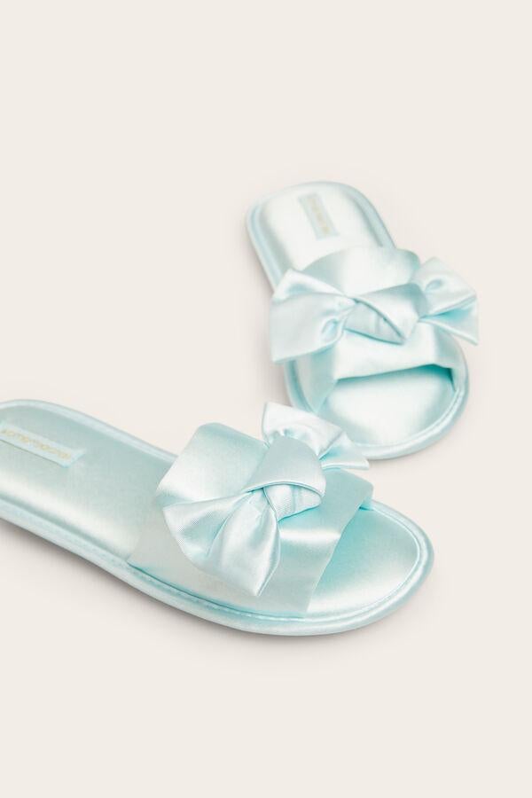 Con un original lazo en el empeine, estas zapatillas de casa de Women Secret en tejido similar al satén están rebajadas, y de 16,99 euros han pasado a 12,99 euros.