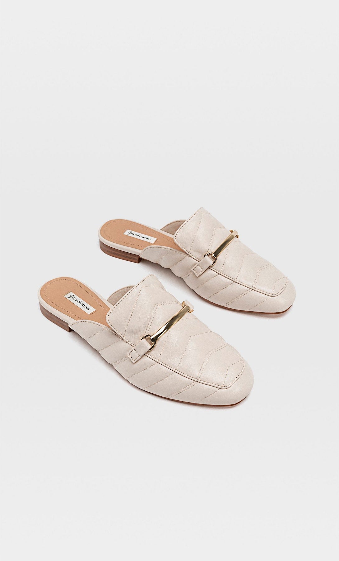 Mule tipo mocasión en tono crudo con detalle metálico de Stradivarius. (25,99 euros).