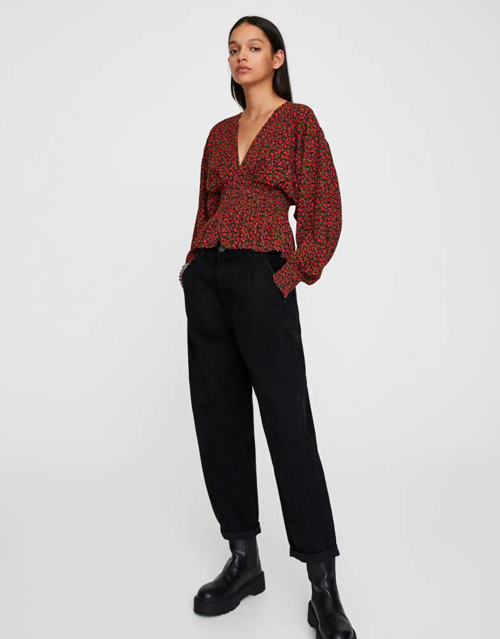 Con fondo negro y flores en tonos rojos y rosas, este top de Pull & Bear se entalla a la cintura con un elástico y sienta de maravilla. De manga larga con volumen, y escote de pico, está disponible de la talla XS a la L y cuesta 19,99 euros.