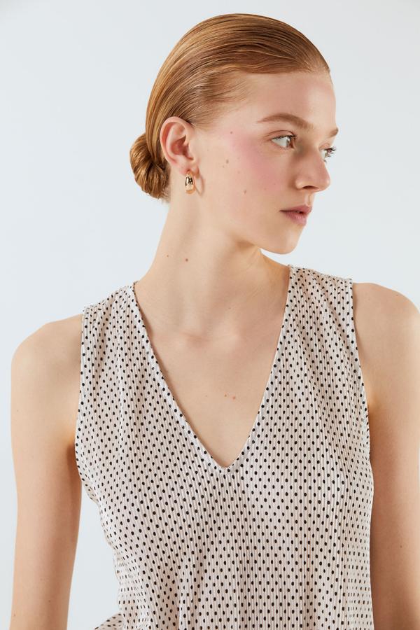 Con minitopos y diseño plisado, esta camiseta de tirantes con cuello de pico en color blanco cuesta 15,99 euros y está disponible en las tallas S, M y L.