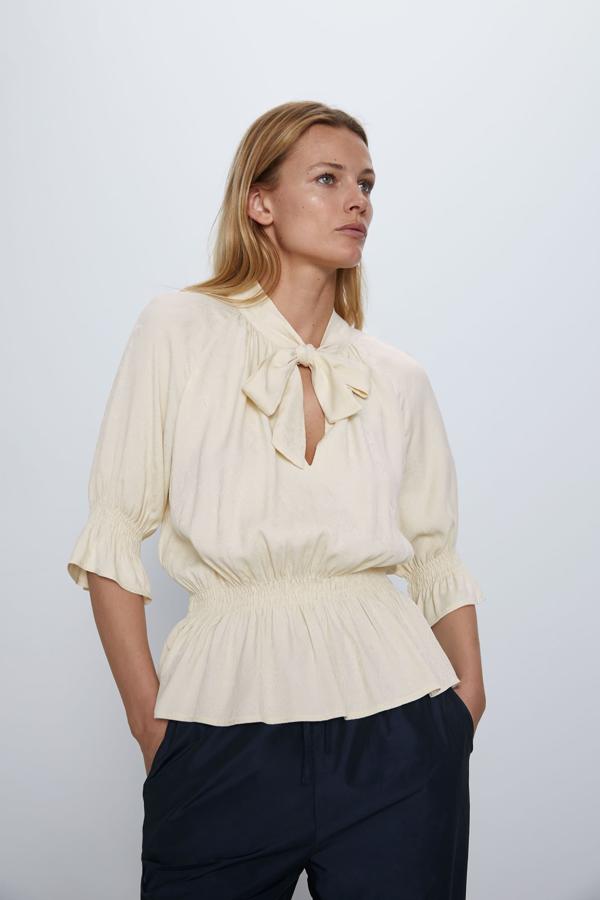 Con gomas en cintura y mangas y lazada en el cuello que se puede llevar suelta o hecha, este modelo en color crudo y tejido satinado es de Zara (25,95 euros).