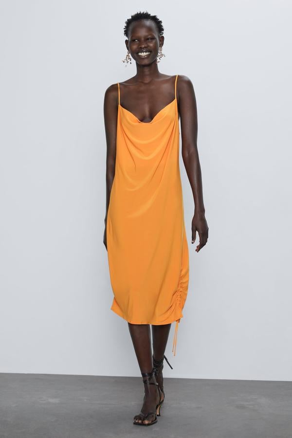En color naranja, este vestido lencero de Zara con escote fluido va a ser un éxito de temporada. Con tirantes finos ajustables, la clave de su diseño es el frunce del bajo. Disponible de la talla S a la XL, tiene un precio fantástico: 17,95 euros.