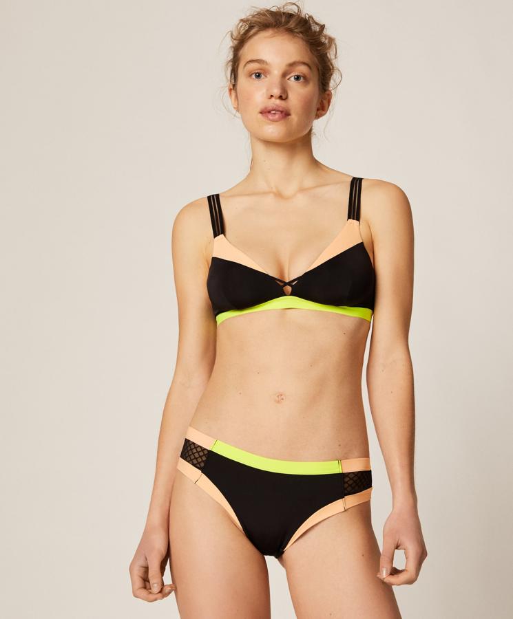 Rompiendo la monocromía habitual de la ropa interior, Oysho nos propone esta opción con el negro como base y formada por sujetador triangular sin relleno ni aro, con goma elástica de color flúor en la parte inferior. La braguita brasileña a juego tiene un detalle de red en los laterales. Este conjunto está rebajado, y mientras que el sujetador cuesta 11,89 euros, la braguita está en 4,89 euros.