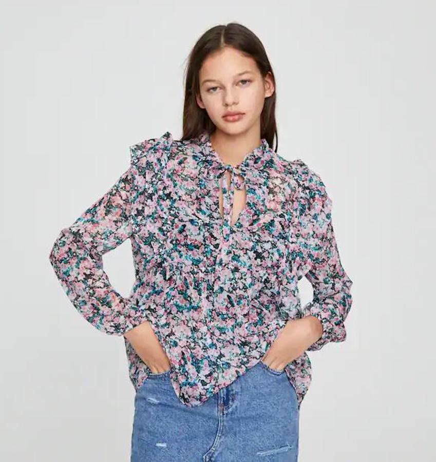 Blusa de flores en tonos rosas y verdes con volantes en el pecho y hombros y el detalle de la lazada en el cuello (9,99 euros).
