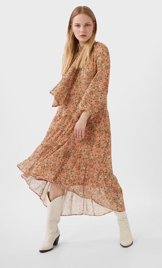 Este vestido midi floreado en tonos naranjas, con lazada al cuello y bajo asimétrico es de Stradivarius. Tiene un precio de 29,99 euros y está disponible en las tallas S, M y L.