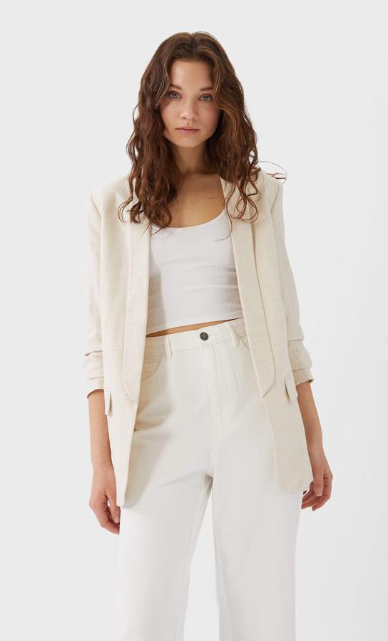 En Stradivarius hemos encontrado esta americana en lino con manga fruncida y cuello de solapa larga sin cierre. En color vainilla, cuesta 29,99 euros y está disponible en las tallas S, M y L.