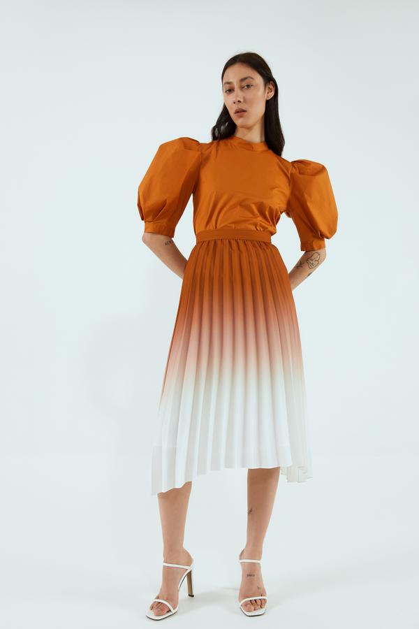 Puestos a alargar nuestra figura, mejor hacerlo con esta falda midi plisada de Sfera en la que su efecto degradado nos ayuda a hacerlo. En naranja y blanco, cuesta 35,99 euros y está disponible en las tallas S, M y L.