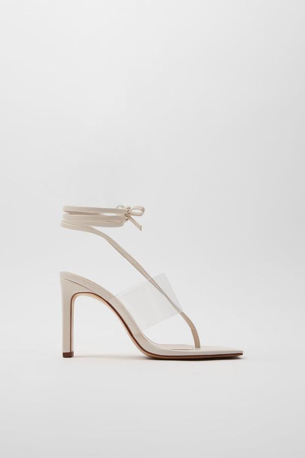 En Zara han unido las tiras en blanco con una banda de vinilo en el empeine para crear estas sandalias de punta cuadrada y tacón rectangular plano forrado. Cuestan 35,95 euros y están disponibles entre los números 35 y 41.