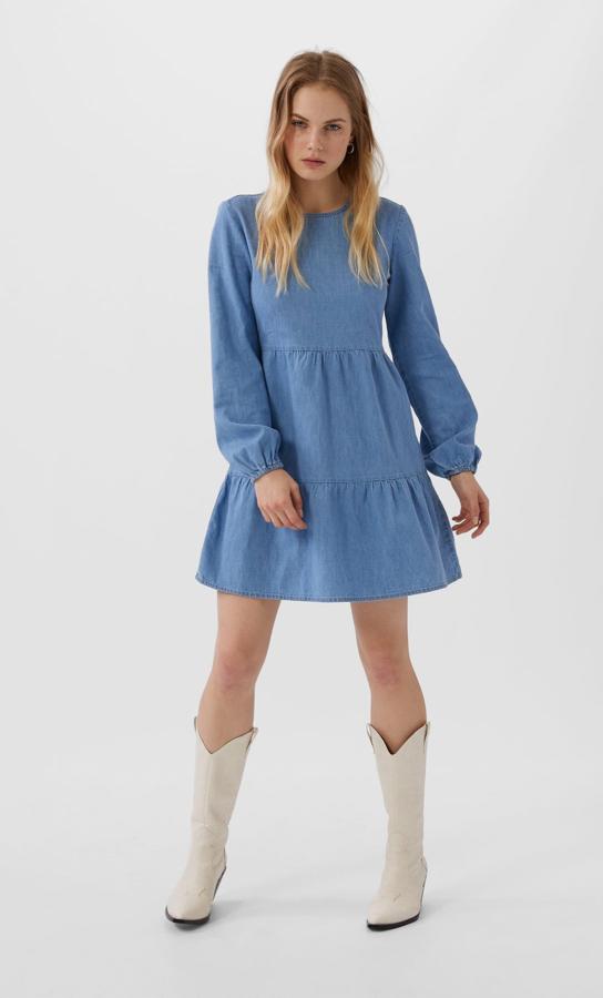 Falda acabada en volantes y mangas largas para este vestido en denim medio de Stradivarius que cuesta 25,99 euros y está disponible en las tallas S y M, aunque la última se está agotando.