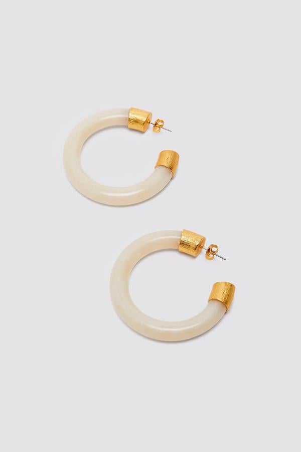 Estos pendientes de aro en dorado y resina blanca no pasarán desapercibidos. Con cierre de tuerca, son de Zara y tienen un precio de 12,95 euros.