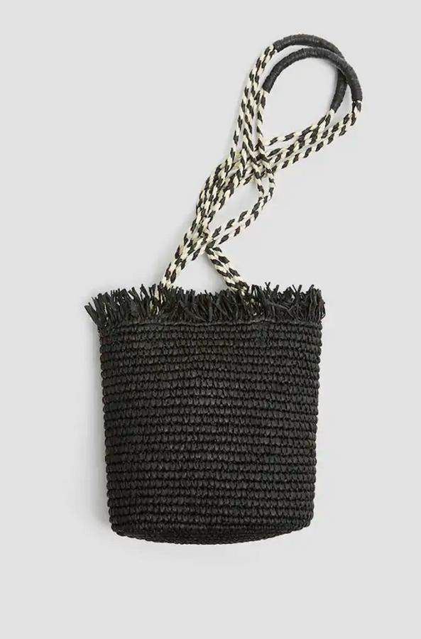 Porque no solo de colores claros viven los estilismos veraniegos, y menos de noche, la firma de Inditex también ha lanzado este bolso formato shopper de papel negro con detalle de asa bicolor. Tiene un precio de 17,99 euros.