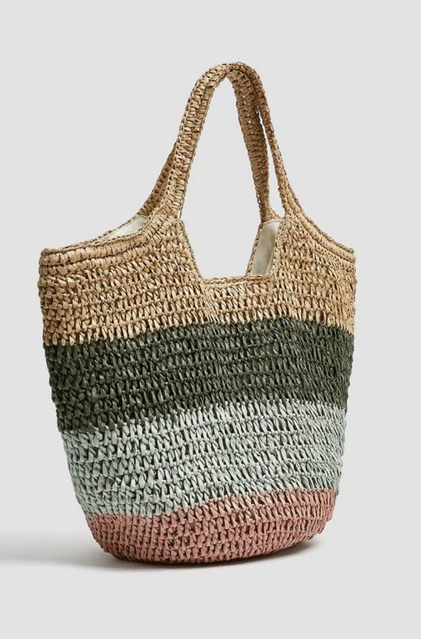 En formato shopper, pero con un diseño que nos recuerda a los veraniegos capazos, este bolso de papel con franjas de colores y forro interior en beige tiene un precio de 25,99 euros.