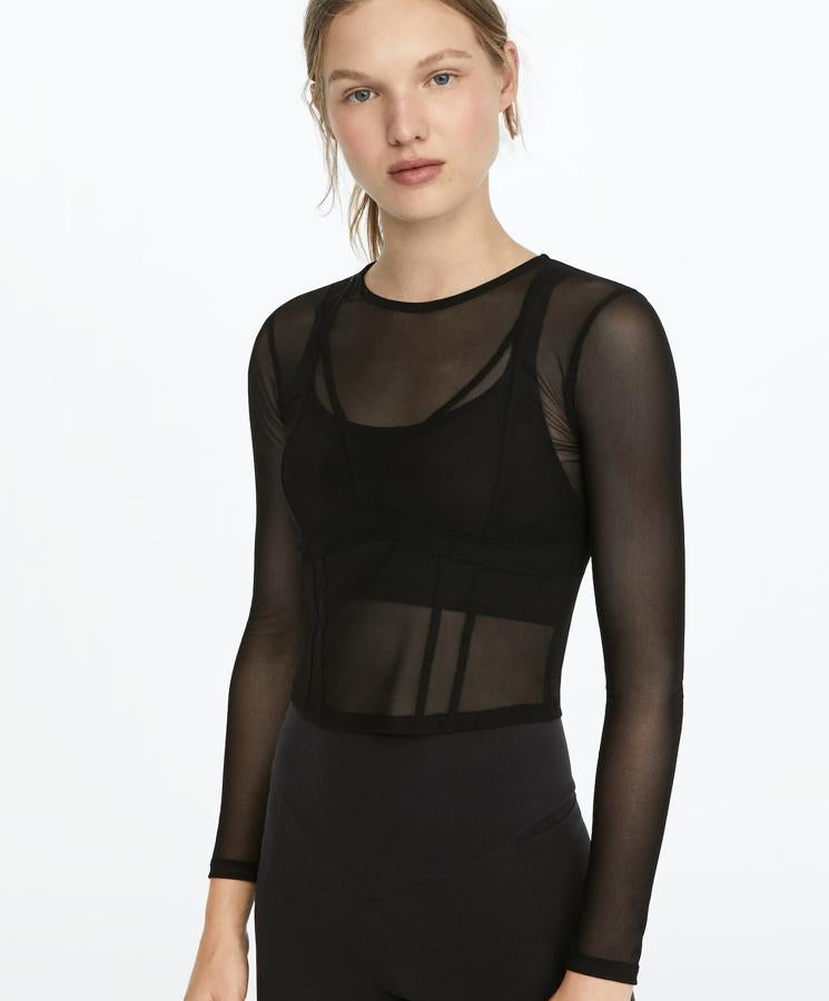 En tejido de tul transparente en color negro, esta camiseta de manga larga cuenta con costuras formado motivos geométricos y tiene un precio de 17,99 euros. Es de Oysho.