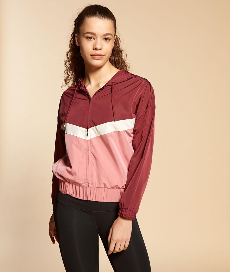 Etam nos propone esta chaqueta deportiva con capucha en color rosa y burdeos. Ajustada a la cintura y cierre con cremallera,  tiene un precio de 39,99 euros.