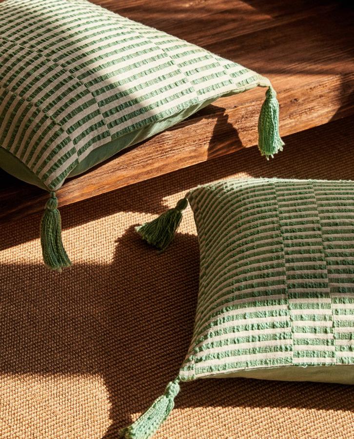 Disponible en menta, amarillo o azul, esta funda de cojín de rayas, de 45 x 45 centímetros y con pompones tiene un precio de 15,99 euros.