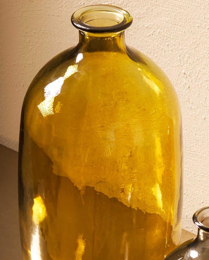 Este jarrón fabricado con vidrio reciclado, es apto para contener agua. Con forma de botella, tiene un precio de 19,99 euros.