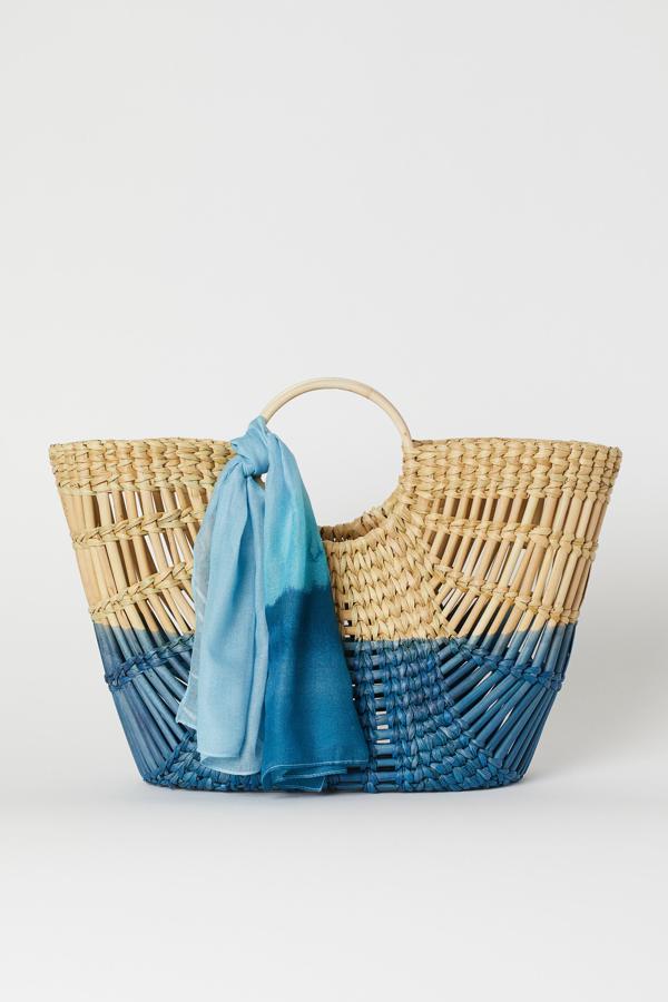 Este bolso artesanal de paja gruesa trenzada con asa redonda está a mitad de precio. Es de H&M y cuesta 24,99 euros. Además, incluye un fular a juego.