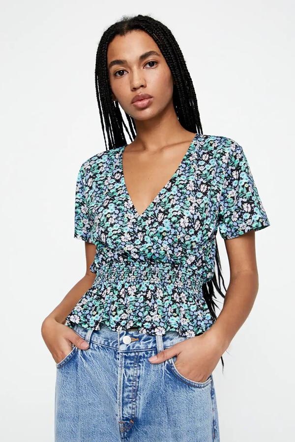 Camiseta con escote de pico cruzado, confeccionado en bambula con estampado de flores en tonos verdes. Es de manga corta y tiene un precio de 15,99 euros.