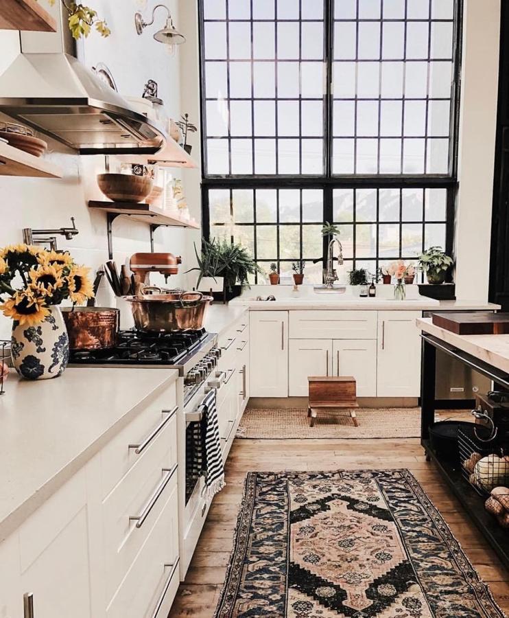 La cocina es uno de los espacios más versátiles de una casa. Según su distribución, puede convertirse incluso en el espacio más transitado. ¿Cómo darle un toque veraniego? Flores y una alfombra vintage, además de un menaje en oro rosa.