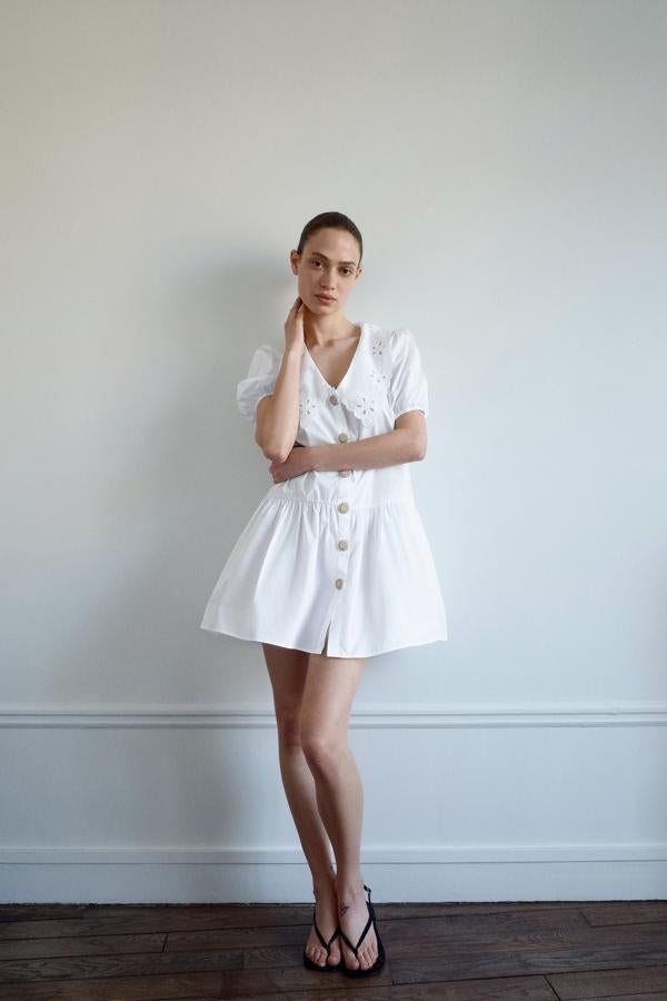 Vestido de popelín en blanco, con botones dorados y cuello bobo calado, de Zara (29,95 euros).