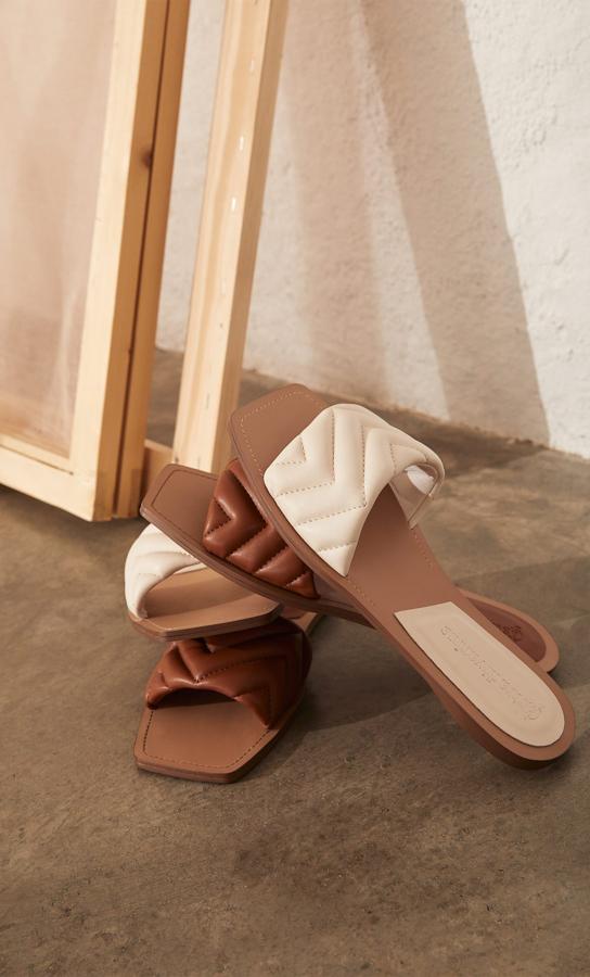 Sandalias planas con tira acolchada disponible en beige y marrón (19,99 euros).