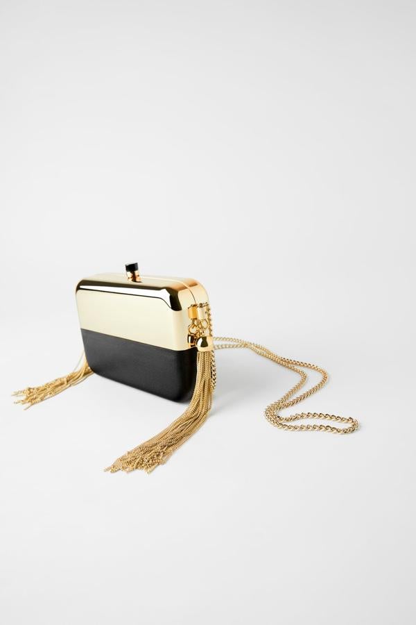 En negro y dorado, este bolso de mano tipo caja de Zara tiene el cuerpo con efecto espejo en combinación de materiales. Con detalle de flecos con cadenas en los laterales, viene con asa de hombro en color dorado y tiene un precio de 29,95 euros.