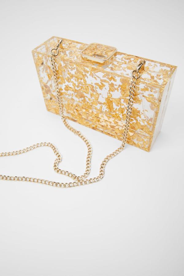 Otra de las propuestas de Zara es este bolso con el cuerpo en metacrilato transparente con detalles en dorado. El mismo color del cierre metálico con imán y el asa de hombro. Cuesta 29,95 euros.