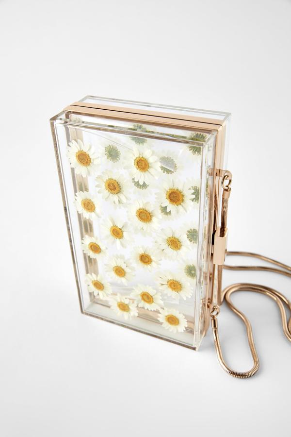 El diseño de Sandra Majada que nos inspiró para esta pequeña colección de bolsos de mano es esta bandolera caja de Zara en metacrilato transparente con detalle de margaritas naturales y dorado en el contorno. El mismo color que vemos en la pieza metálica del cierre y el asa del hombro. Cuesta 35,95 euros.