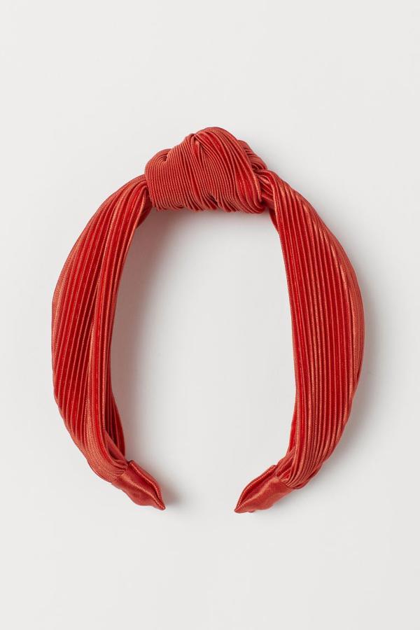 En H&M hemos encontrado una de las propuestas más elegantes con esta diadema plisada con nudo en la parte superior en color naranja. Cuesta 7,99 euros.